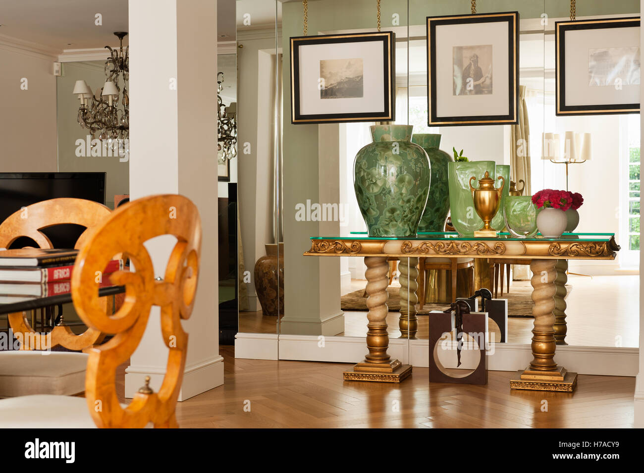 Grüne Gläser auf gold metallic Konsole Spiegelwand im Wohnzimmer mit Säule im Königreich nach Hause Stockfoto