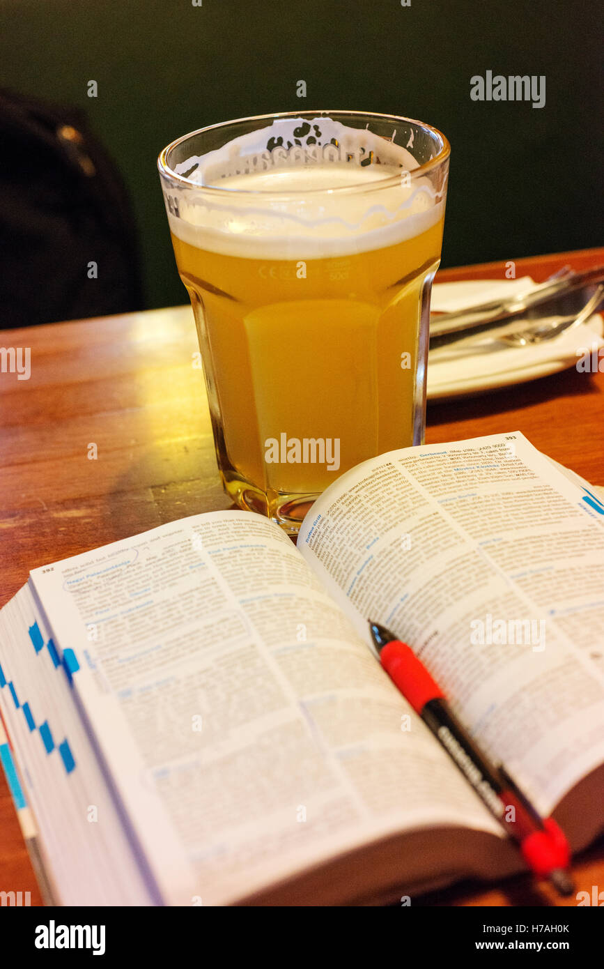 Großes Glas Bier trank bei der Planung von Reisen, mit Reiseführer Buch. Stockfoto
