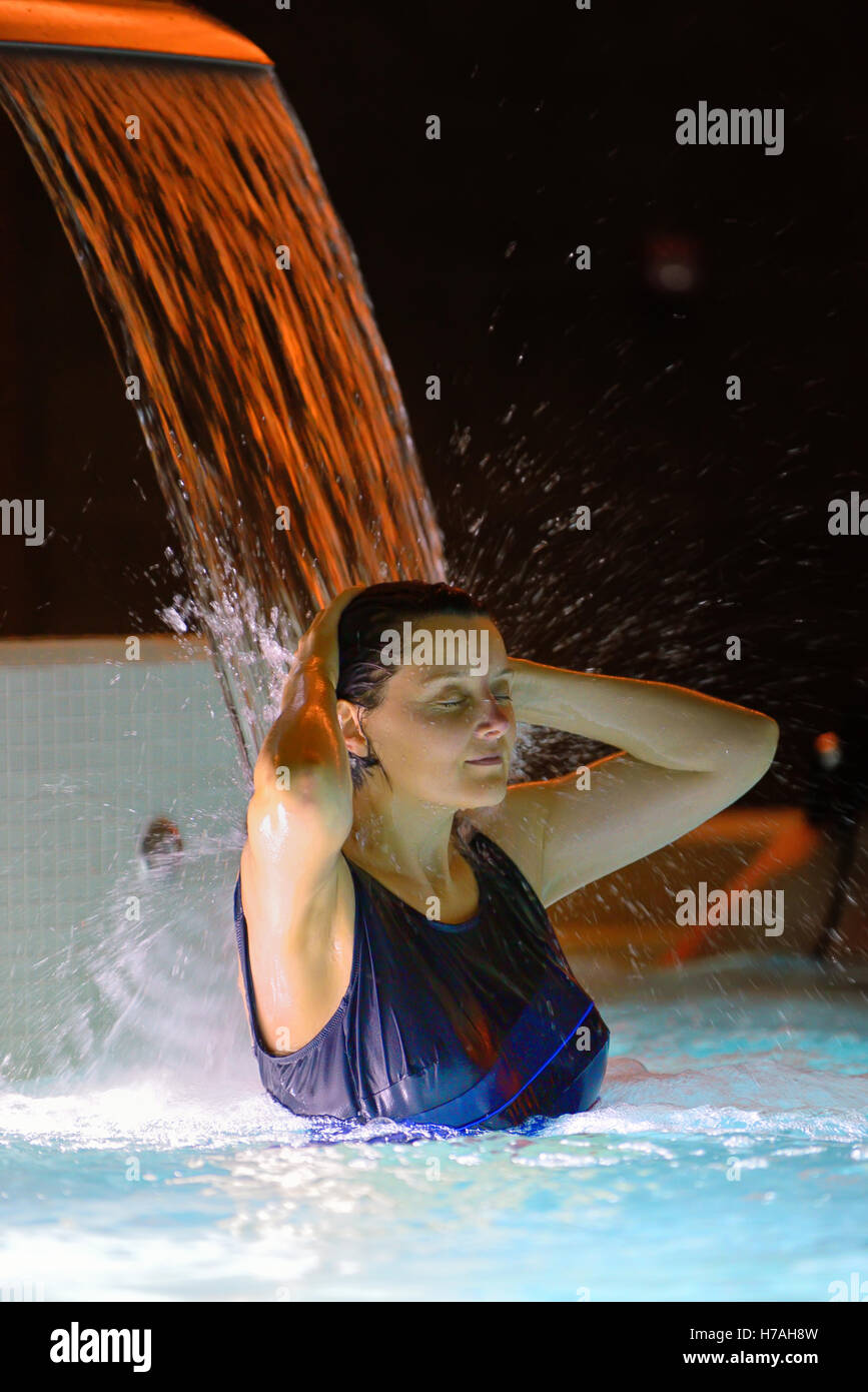 Frau Entspannung im Pool mit Wasserfall Stockfoto