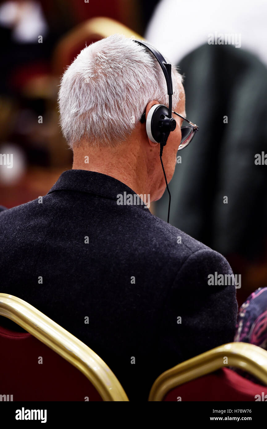 Unerkennbar Person mit in-Ear-Kopfhörer für Übersetzung während der Veranstaltung Stockfoto