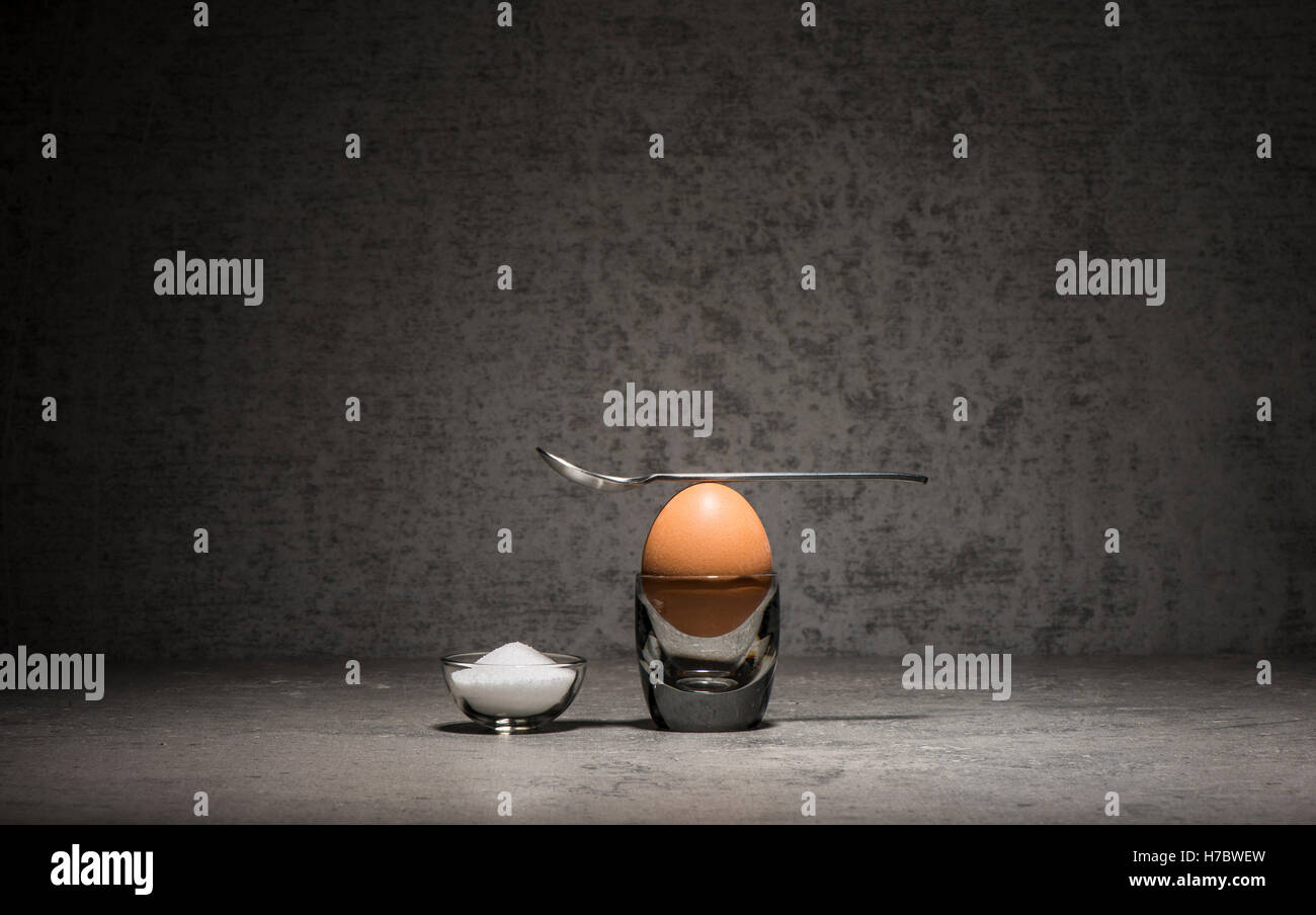 Frühstück-Stillleben. Braune Ei im Eierbecher, eine kleine Schüssel mit Salz und einem Löffel auf Stein Küchentisch. Stockfoto