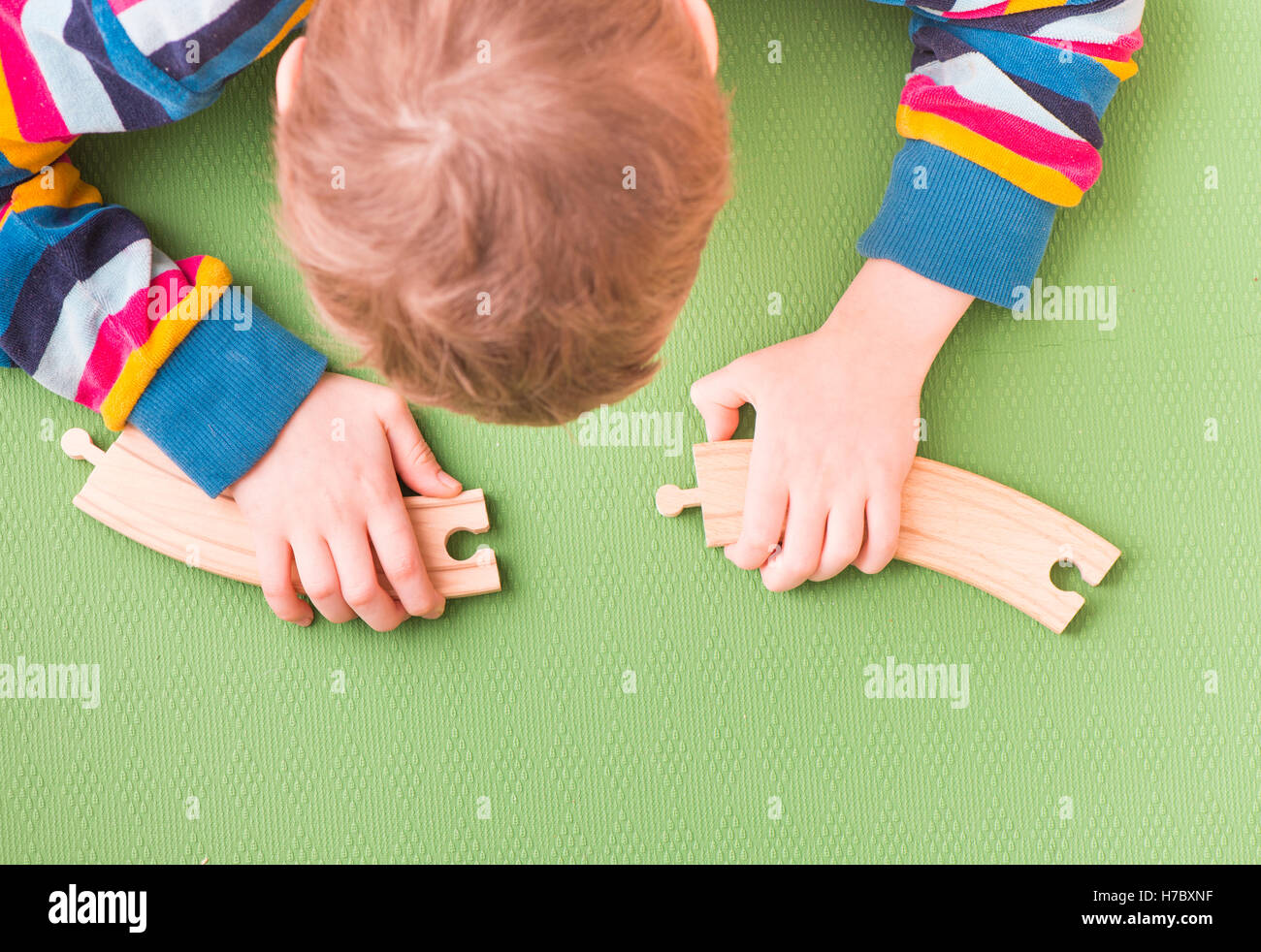 Kind spielt mit Holzspielzeug Eisenbahn verfolgt. Zwei Teile zusammensetzen. Konzept der Kindheit lernen und Probleme zu lösen. Stockfoto