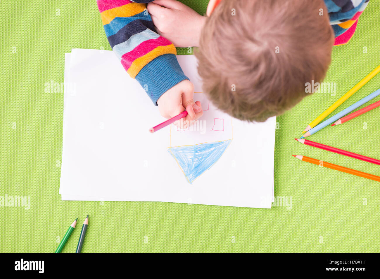 Die Kinder zeichnen ein Haus mit bunten Stiften auf weißem Papier. Konzept von Kindheit, lernen, Spaß, Bildung und Kreativität. Stockfoto