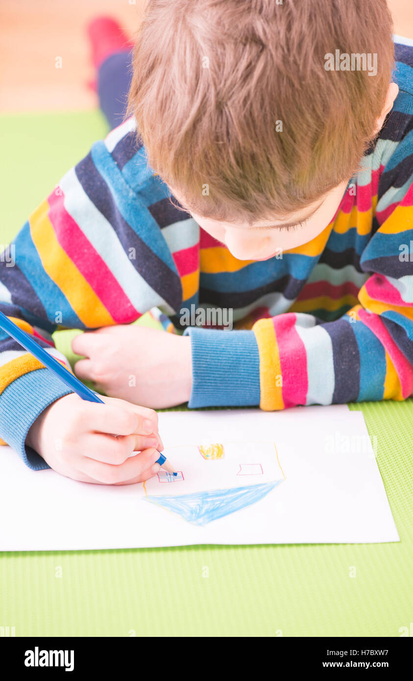 Die Kinder zeichnen ein Haus mit bunten Stiften auf weißem Papier. Konzept von Kindheit, lernen, Spaß, Bildung und Kreativität. Stockfoto