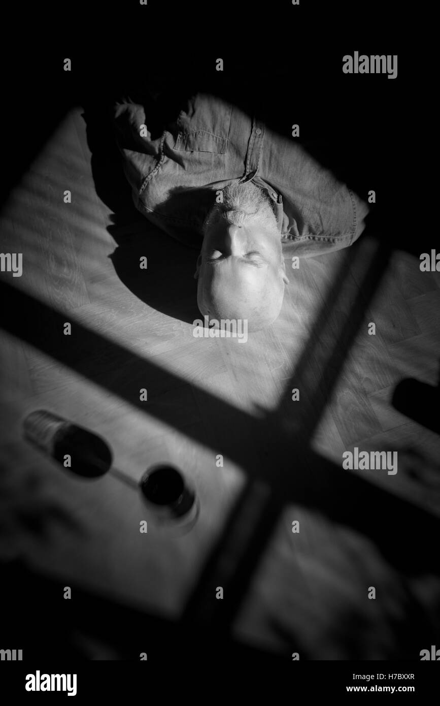 Alter Mann auf Boden ruhen. Schwarz-weiß-Porträt mit tiefen Schatten. Konzeptbild von Einsamkeit und Ruhestand. Stockfoto