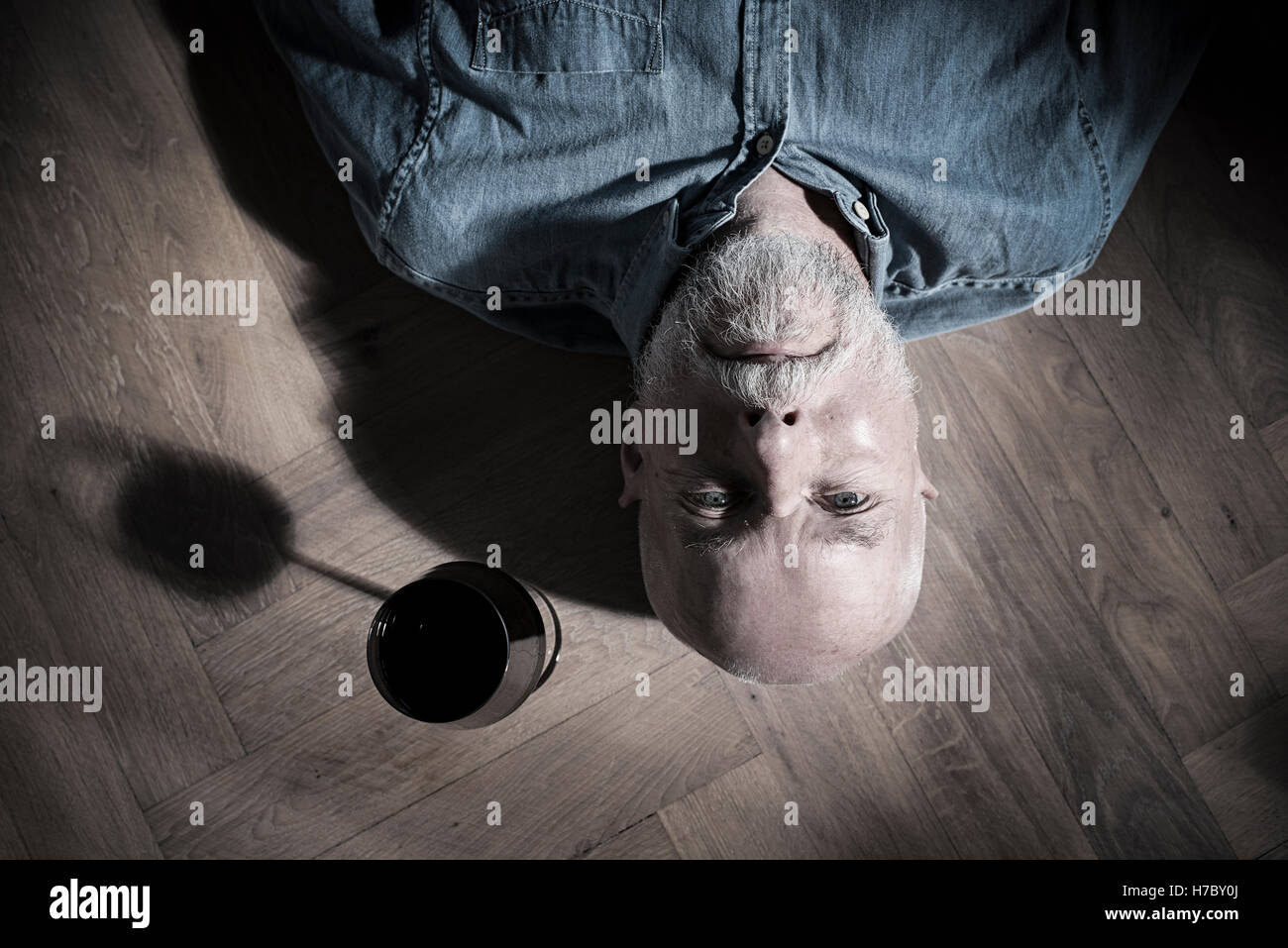 Alter Mann mit Weinglas auf der Seite auf Boden ruhen. Konzeptbild von Einsamkeit und Ruhestand. Stockfoto