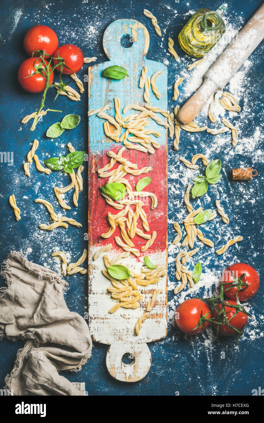 Zutaten für das italienische Abendessen kochen. Frische Pasta Casarecce, Cherry-Tomaten, Basilikum und Flasche Olivenöl auf bunten Stockfoto