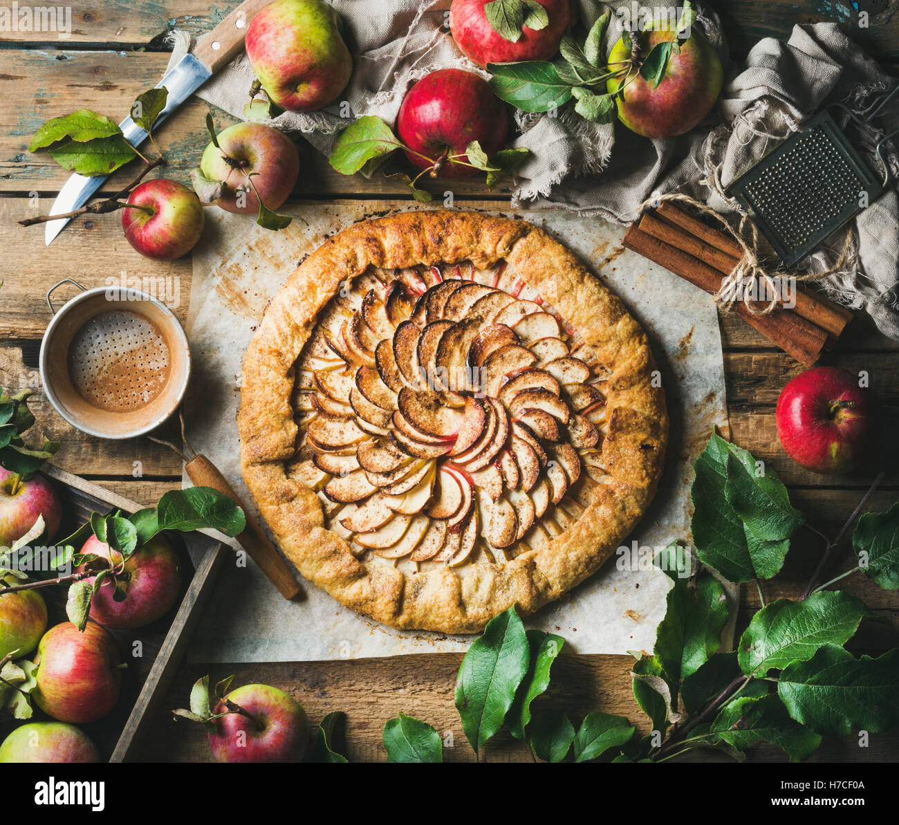 Crostata Apfelkuchen mit Zimt serviert mit frischen Garten Äpfel mit Blättern auf rustikalen hölzernen Hintergrund, Draufsicht, horizontale c Stockfoto