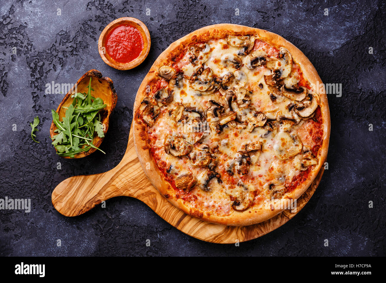 Pizza mit Pilzen auf Holz Oliven Schneidebrett auf dunklem Hintergrund Stockfoto