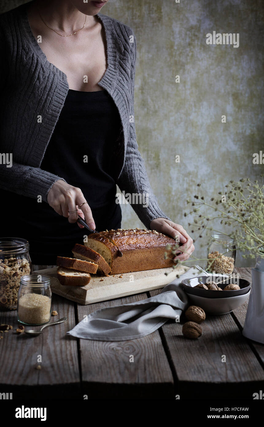 Frau schneiden Müsli Kuchen auf einem rustikalen Holztisch Stockfoto