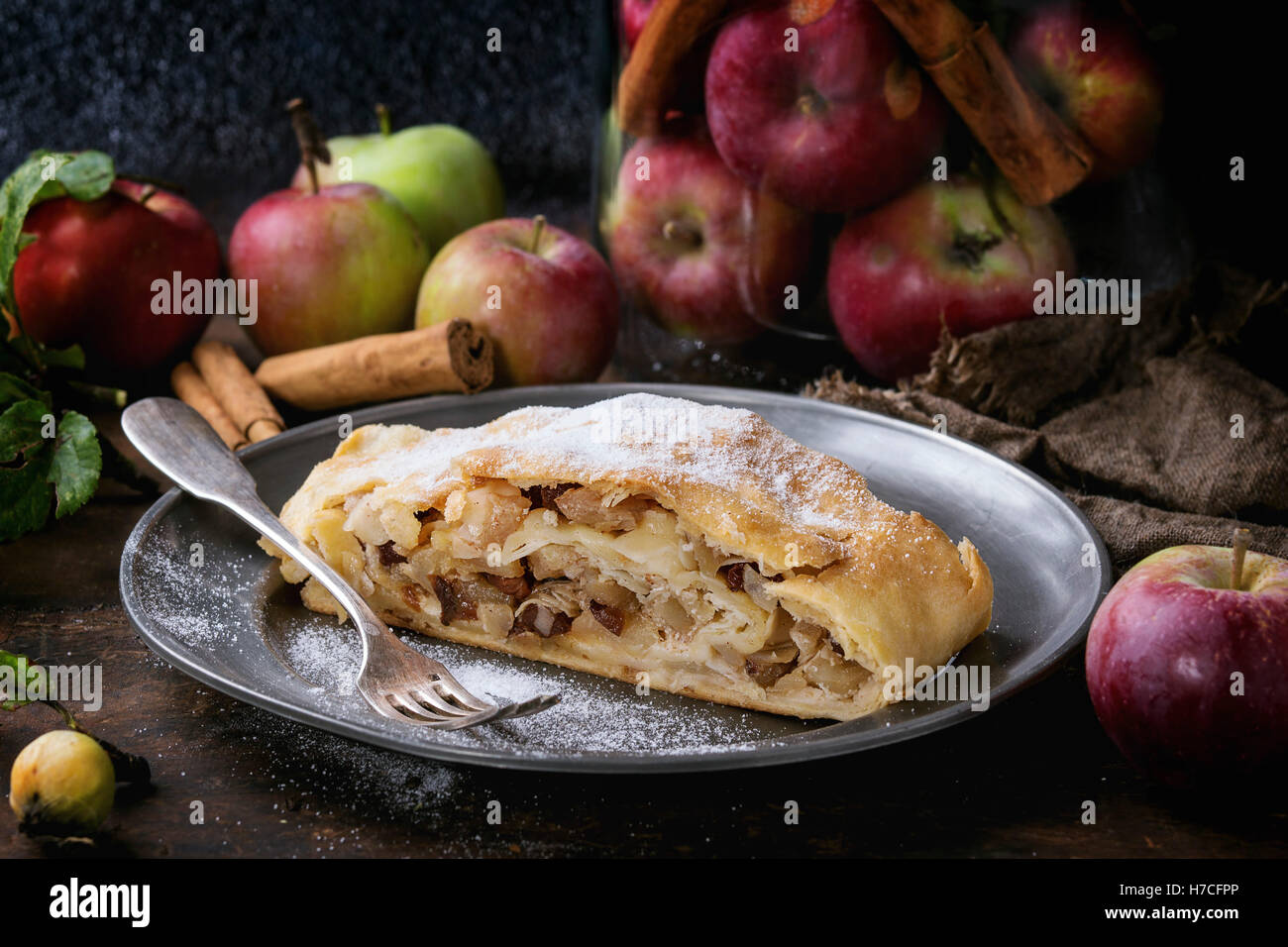In Scheiben geschnitten serviert mit frischen Äpfeln im Glas hausgemachten Apfelstrudel, Zimtstangen und Puderzucker auf Vintage Metall Platte Witz Stockfoto