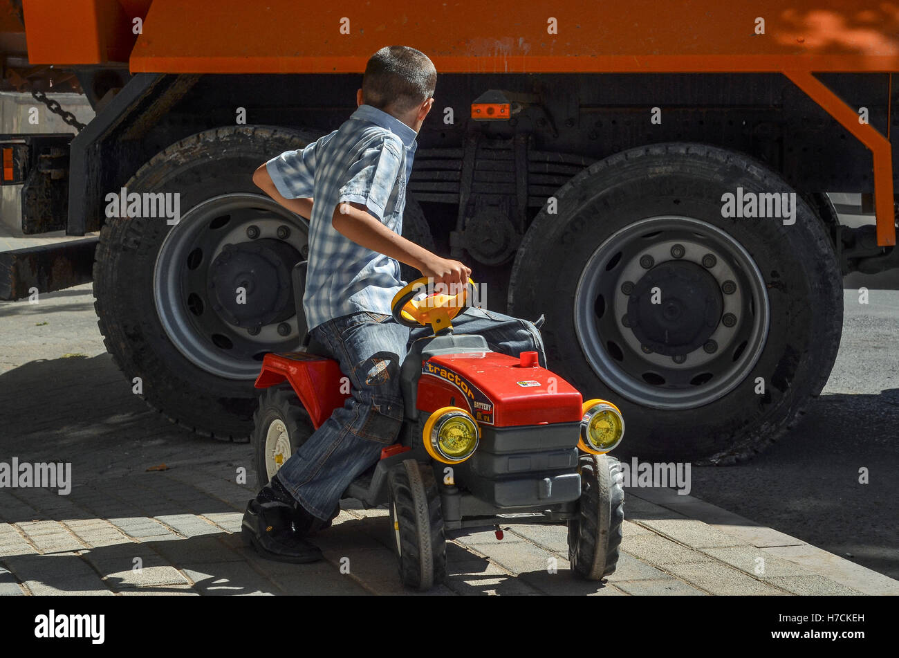 Ein Junge spielt mit einem Spielzeug-Traktor auf einer Straße in Istanbul. Stockfoto