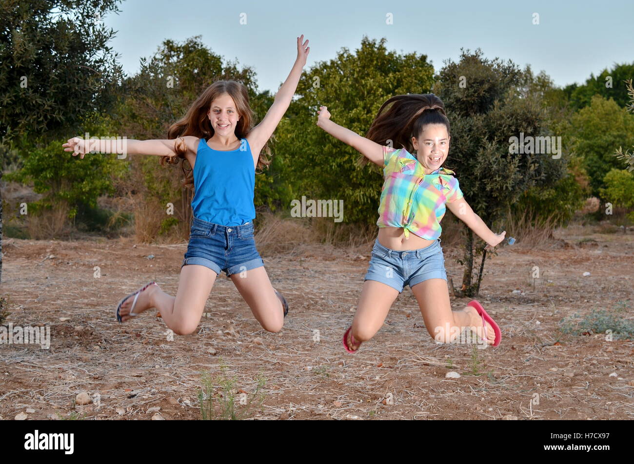 Beste Freunde für immer - zwei 12-jährige Mädchen im Teenageralter springen in der Luft eingefroren Stockfoto