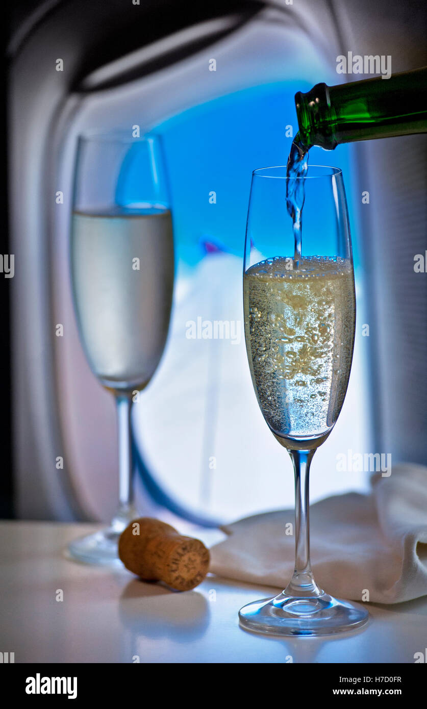FIRST CLASS Luxus fliegen Gießen Champagner während des Fluges in Luxus-Kabine mit Fenster und Flugzeug Flügel hinter Stockfoto