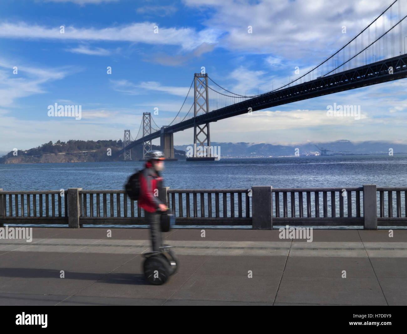 Mann mit Geschwindigkeit auf Segway elektrischer Personenbeförderung auf Embarcadero mit Bay Bridge hinter San Francisco Kalifornien, USA Stockfoto