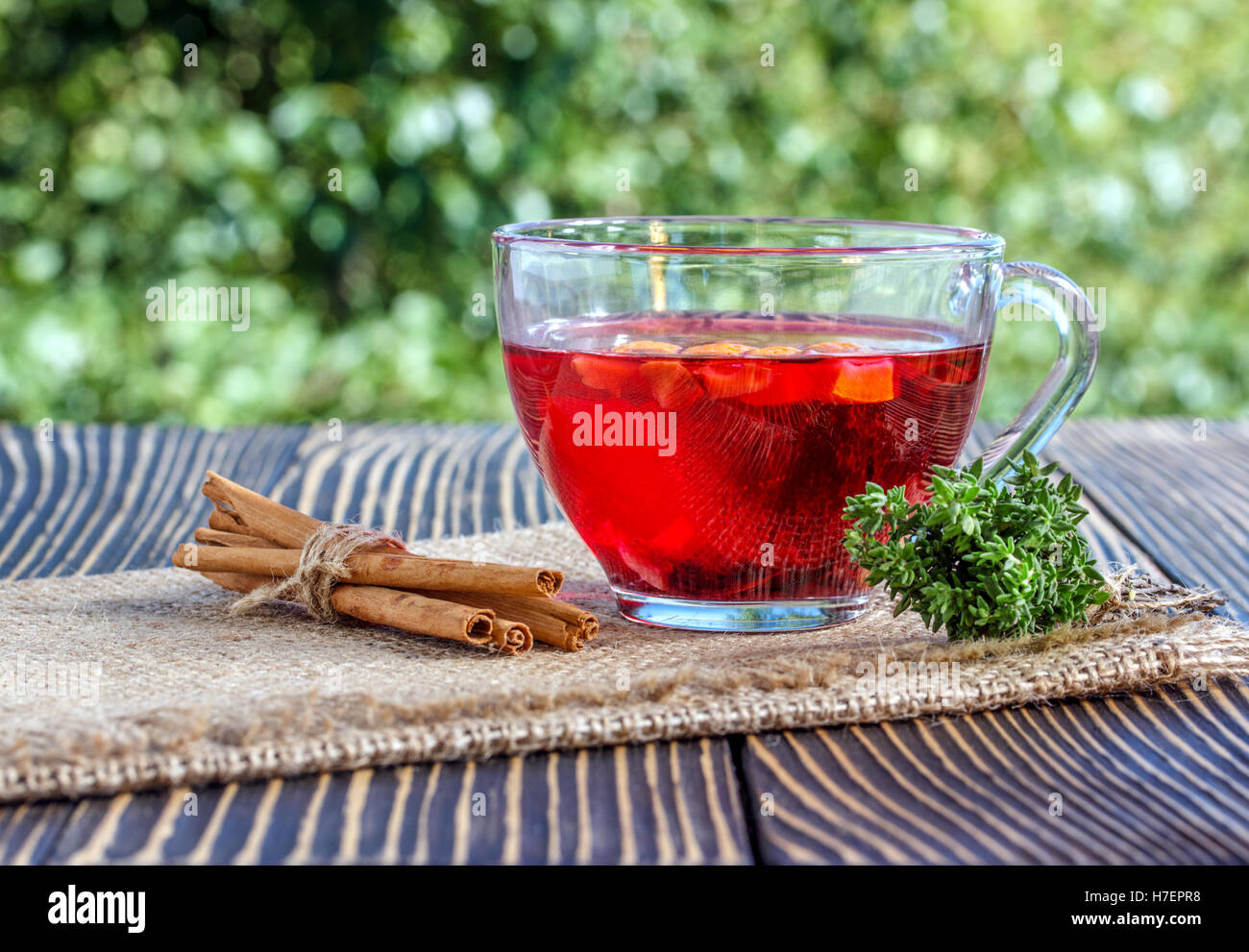 Tasse Tee mit verschiedenen Kräutern und getrockneten Früchten auf einem Holztisch im freien Stockfoto