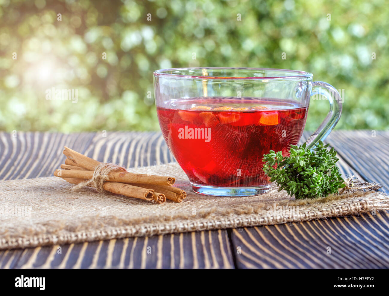 Tasse Tee mit verschiedenen Kräutern und getrockneten Früchten auf einem Holztisch im freien Stockfoto