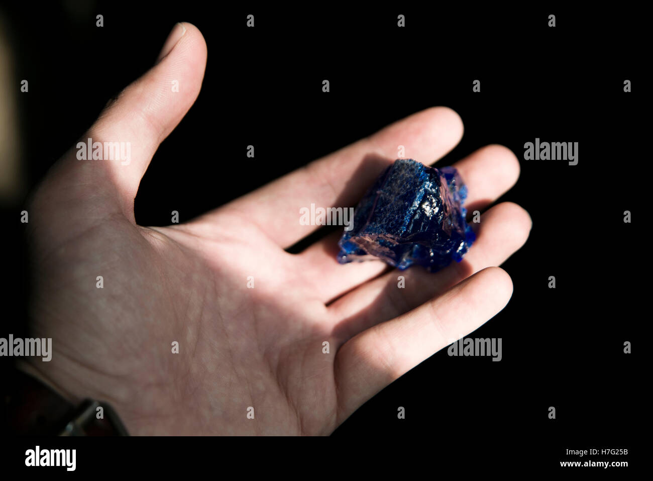 Blaues Glas auf eine Hand gebrochen. Das Glas wird verwendet und geschmolzen um Amulett später zu produzieren. Stockfoto