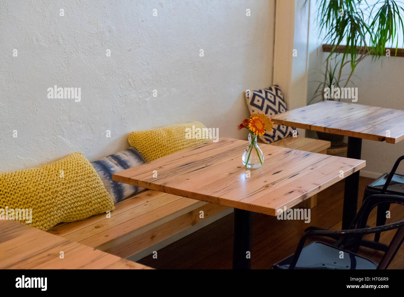 Sitzbank in einem Café-Restaurant mit kleinen Café-Tischen und Kissen. Stockfoto