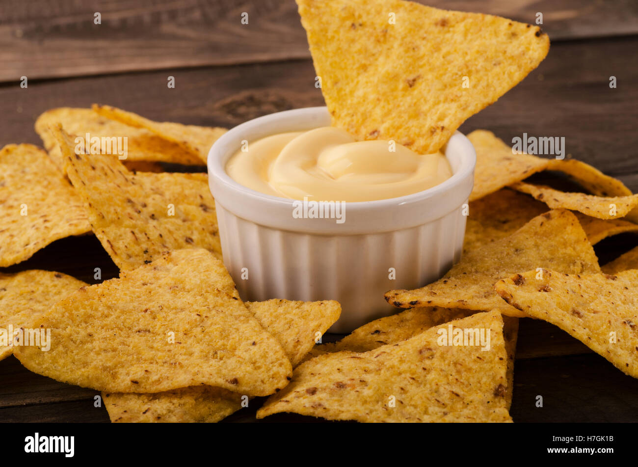 Nachos mit Käse-Dip auf einem Holztisch Stockfoto