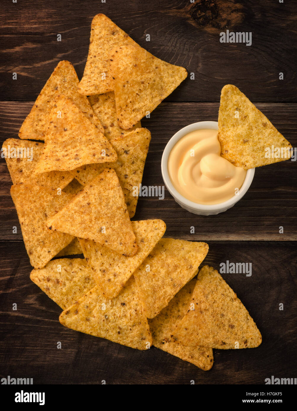 Nachos mit Käse-Dip auf einem Holztisch, Ansicht von oben Stockfoto