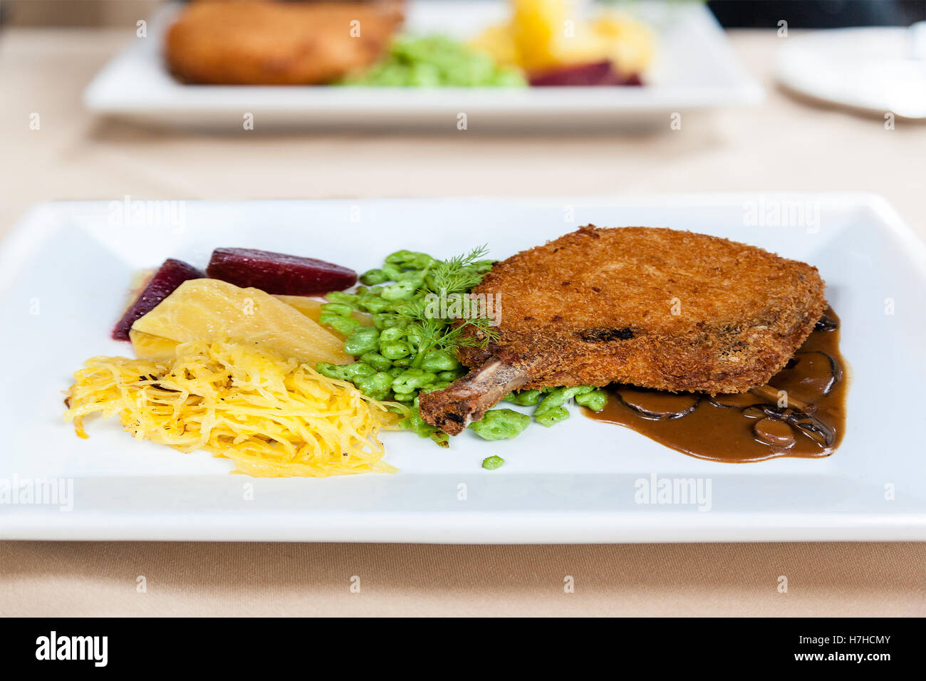 Knusprig gebratene Honig glasierte Schweinekotelett mit Gemüse, süße Kartoffelchips und Marsala Portobello Pilzsauce. Stockfoto