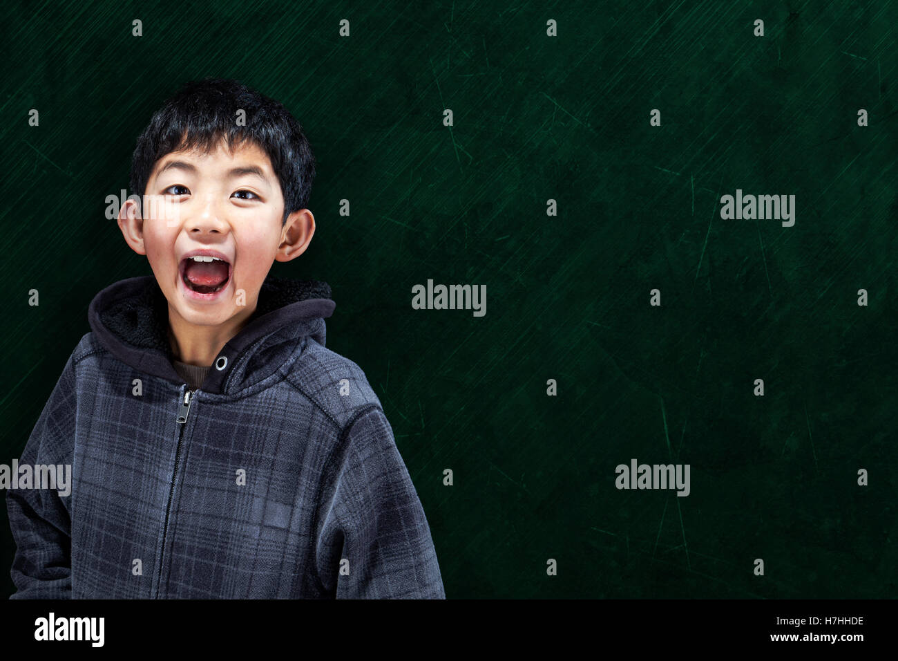 Intelligente Asian Boy mit im Klassenzimmer mit Tafel Hintergrund und Kopie Stockfoto