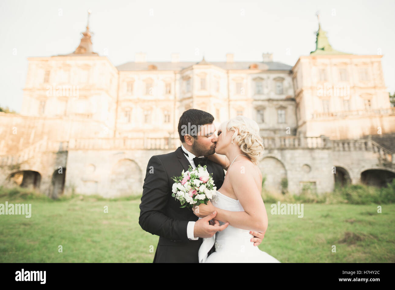 Glückliche Hochzeit paar umarmen und küssen auf Hintergrund altes Schloss Stockfoto