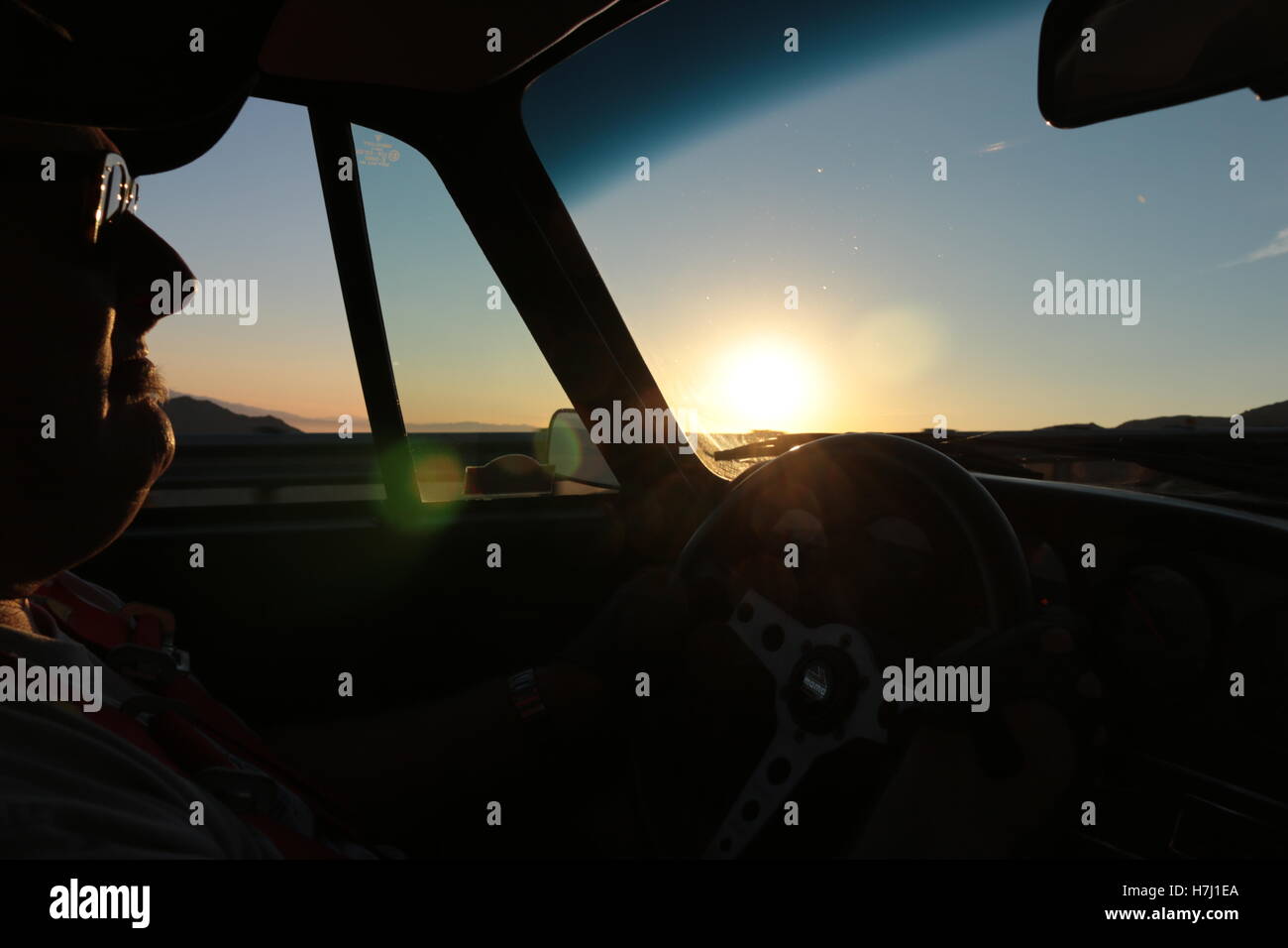 Mann fahren eines Sportwagens im frühen Morgenlicht Stockfoto
