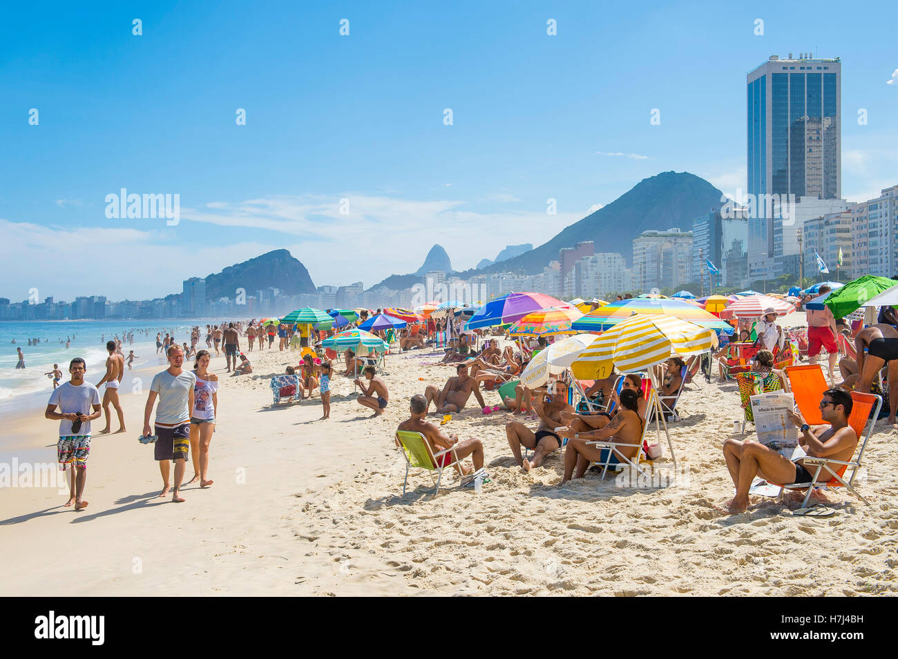 RIO DE JANEIRO - 27. Februar 2016: Massen der Strandbesucher füllen Copacabana-Strand mit bunten Sonnenschirmen am hellen Nachmittag. Stockfoto