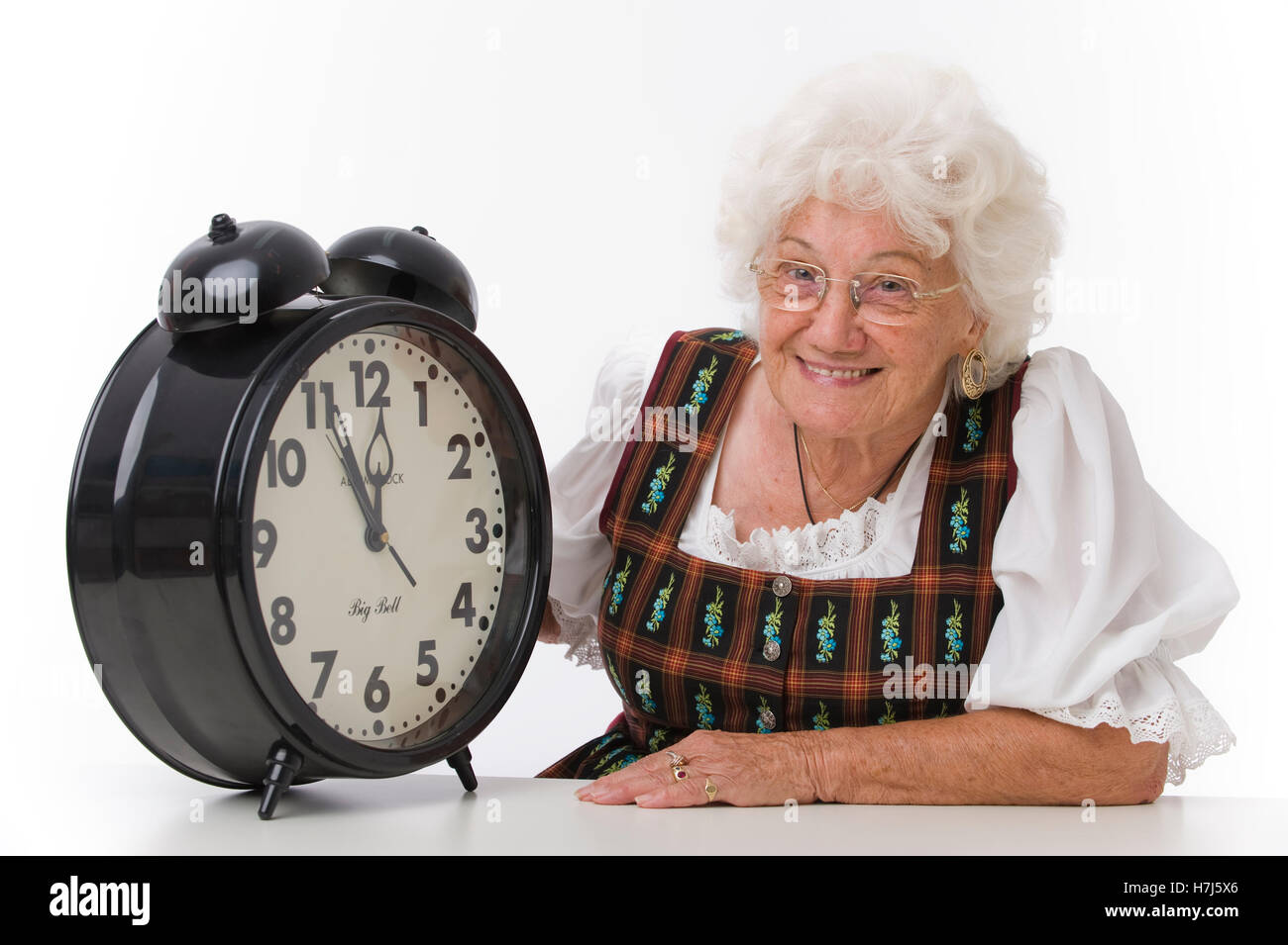 Es ist fast zwölf Uhr mittags, ältere Frau mit einem Wecker Stockfoto