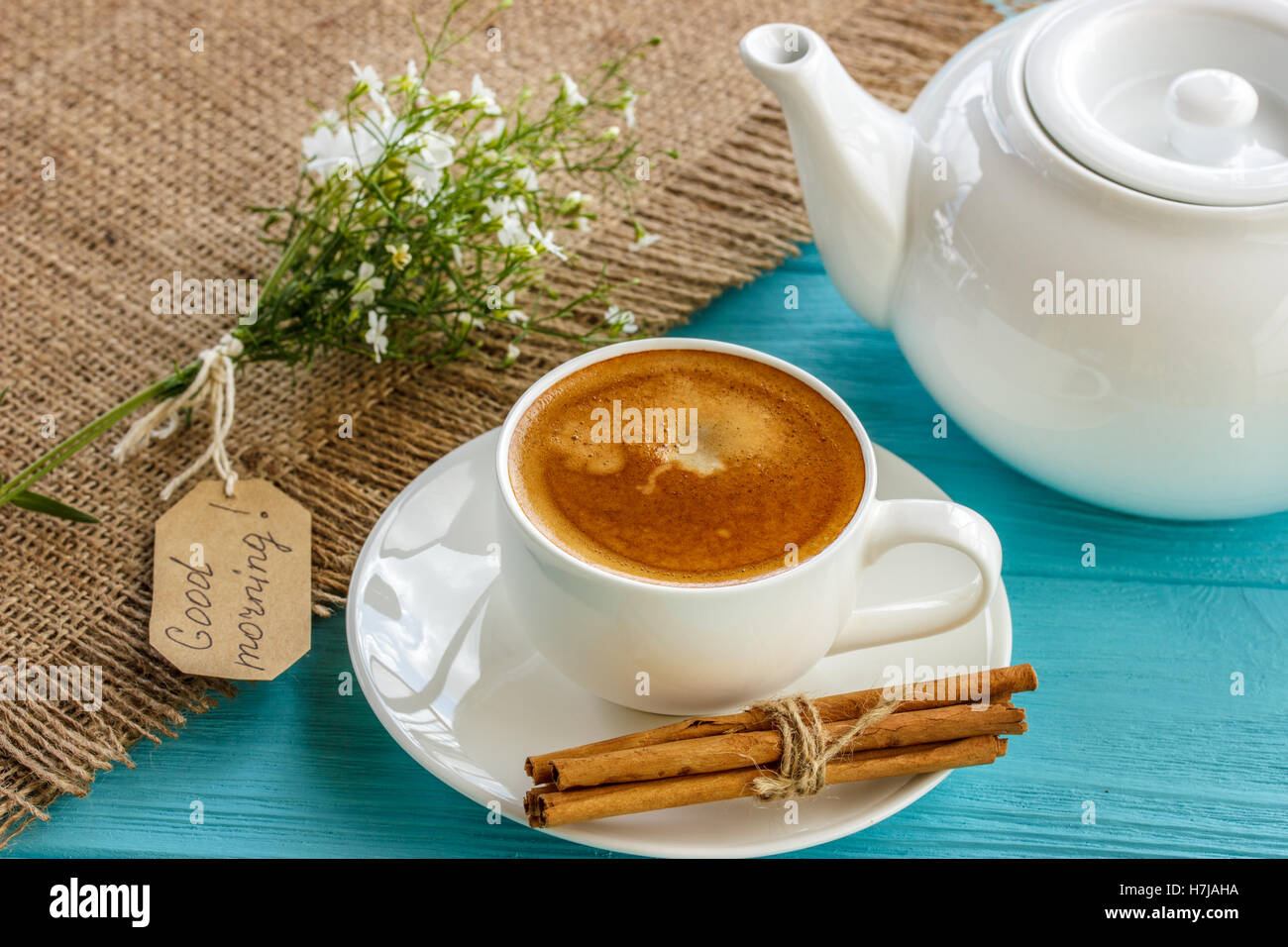 Kaffeebecher mit weißen Blüten und Notizen guten Morgen Frühstück am blauen rustikalen Tisch von oben, Stockfoto