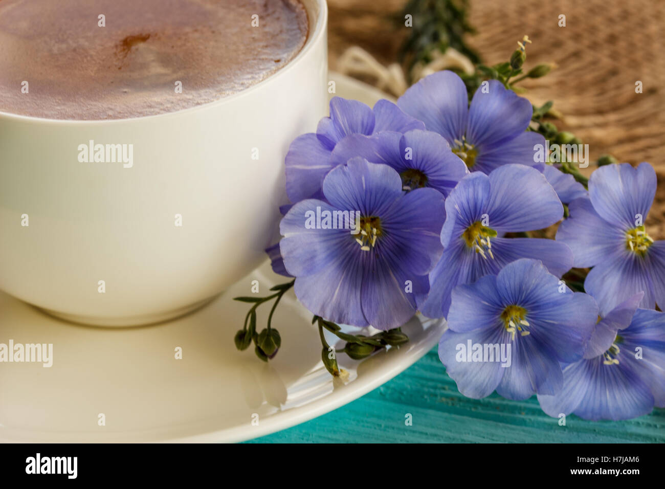 Kaffeebecher mit blauen Blüten und Notizen guten Morgen Frühstück am blauen rustikalen Tisch von oben, Stockfoto