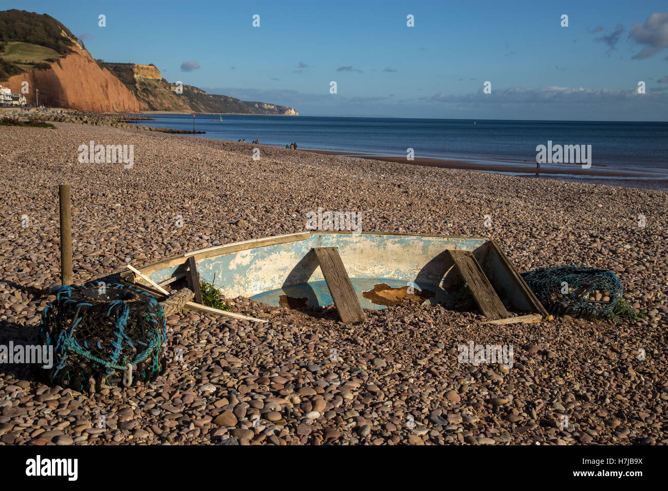Ein kleines Boot fast begraben unter Kies am Strand in Sidmouth, Devon Stockfoto