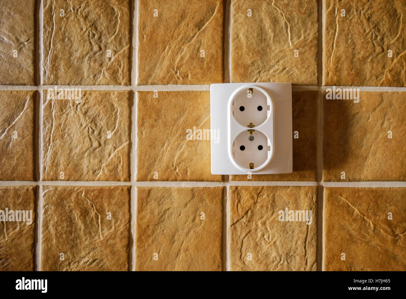 Weiße Steckdose an Küchenwand mit Keramikfliesen Muster Textur Stockfoto
