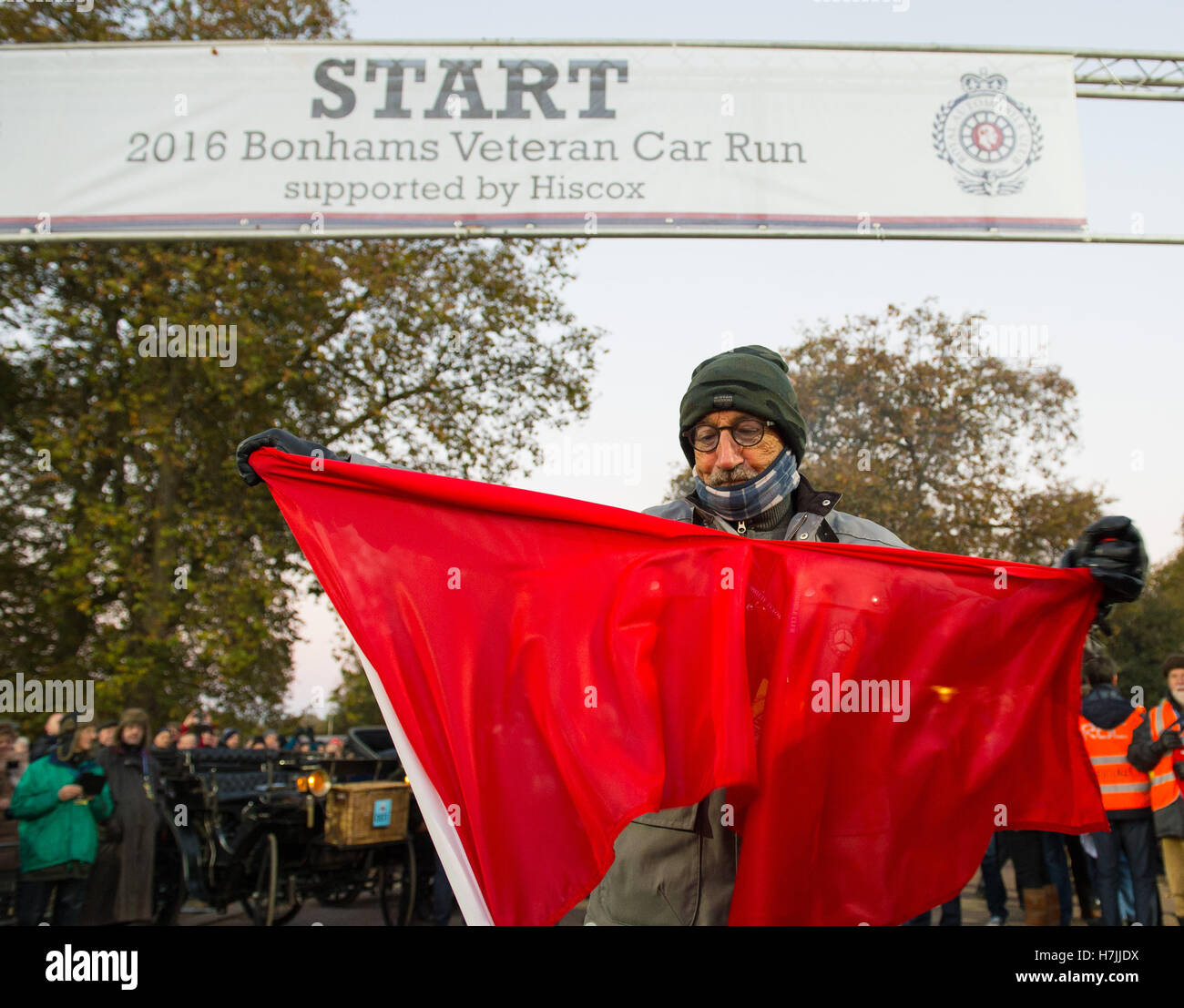 NUR zur redaktionellen Nutzung Eddie Jordan führt das traditionelle zerreißen die rote Flagge zu Beginn der Bonhams London to Brighton Veteran Car Run am Hyde Park Corner in London. Stockfoto