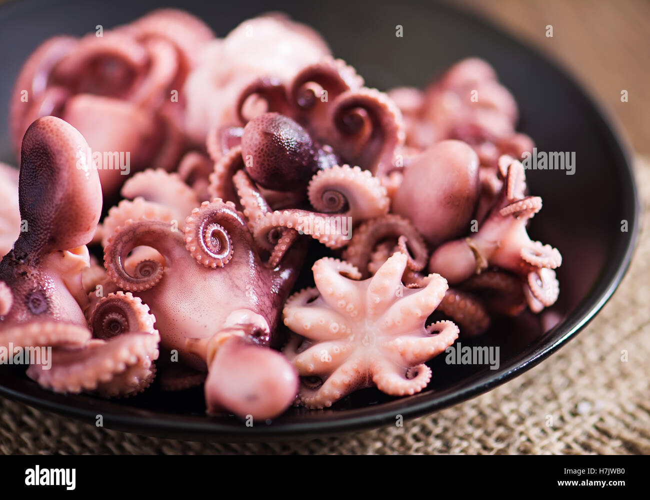 Gekochte kleine Krake auf einer schwarzen Platte Stockfoto