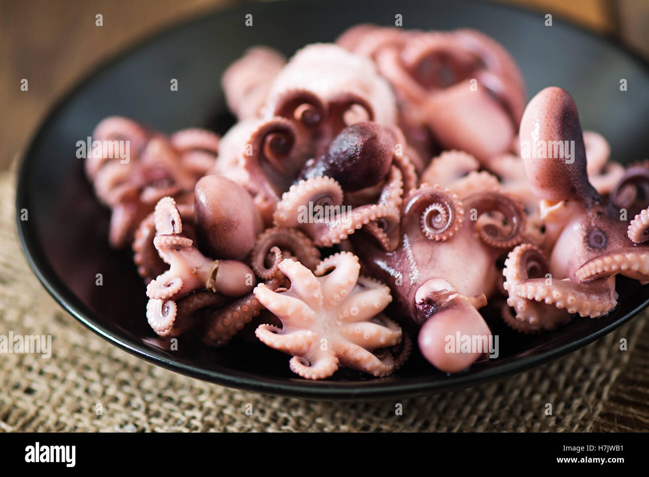 Gekochte kleine Krake auf einer schwarzen Platte Stockfoto