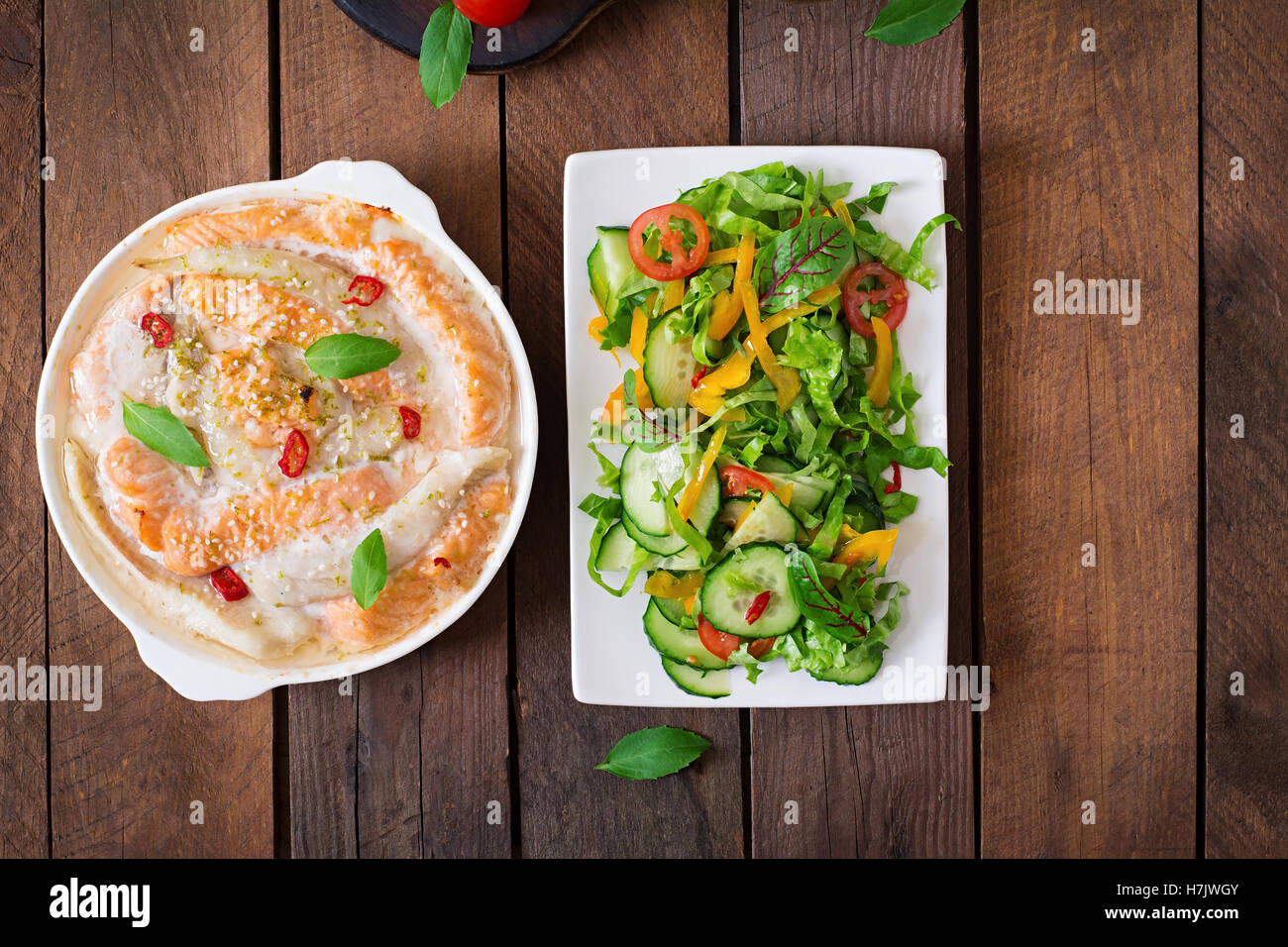 Gebackene Scheiben der roten und weißen Fisch mit Honig und Zitronensaft, mit frischem Salat serviert. Ansicht von oben Stockfoto