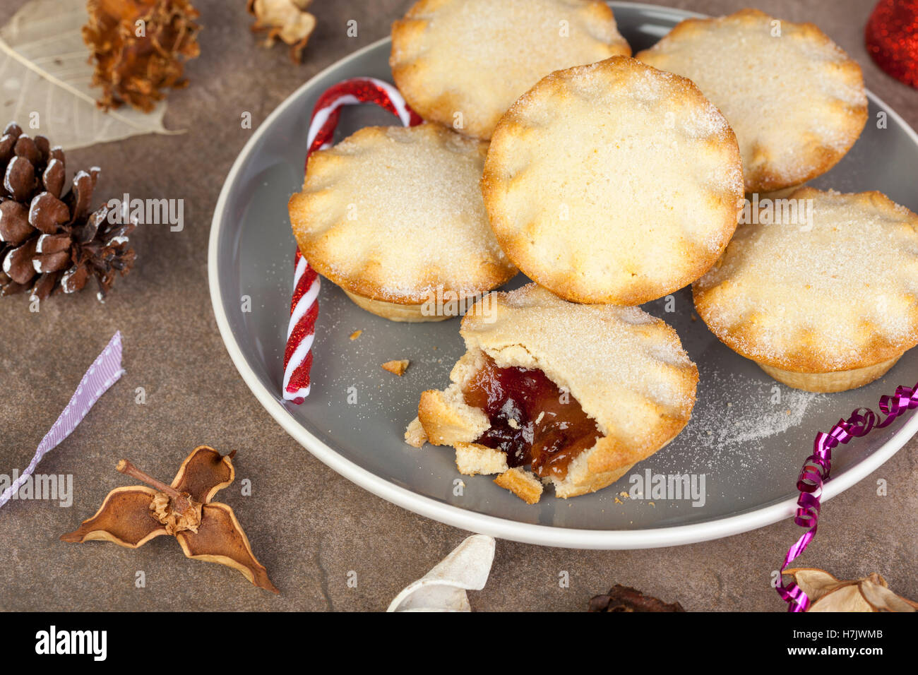 Sechs vergoldete Mince Pies auf eine festliche Weihnachten Tabelle mit Biss und aus dem einen von Ihnen getroffen Stockfoto