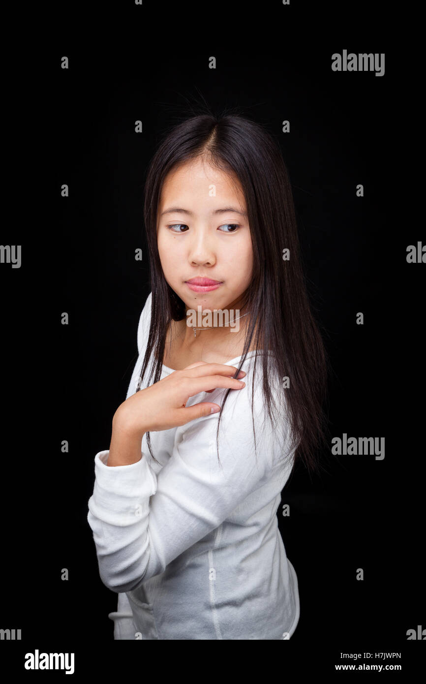Modische Teen Asiatin auffällig eine Pose, auf schwarzem Hintergrund isoliert Stockfoto