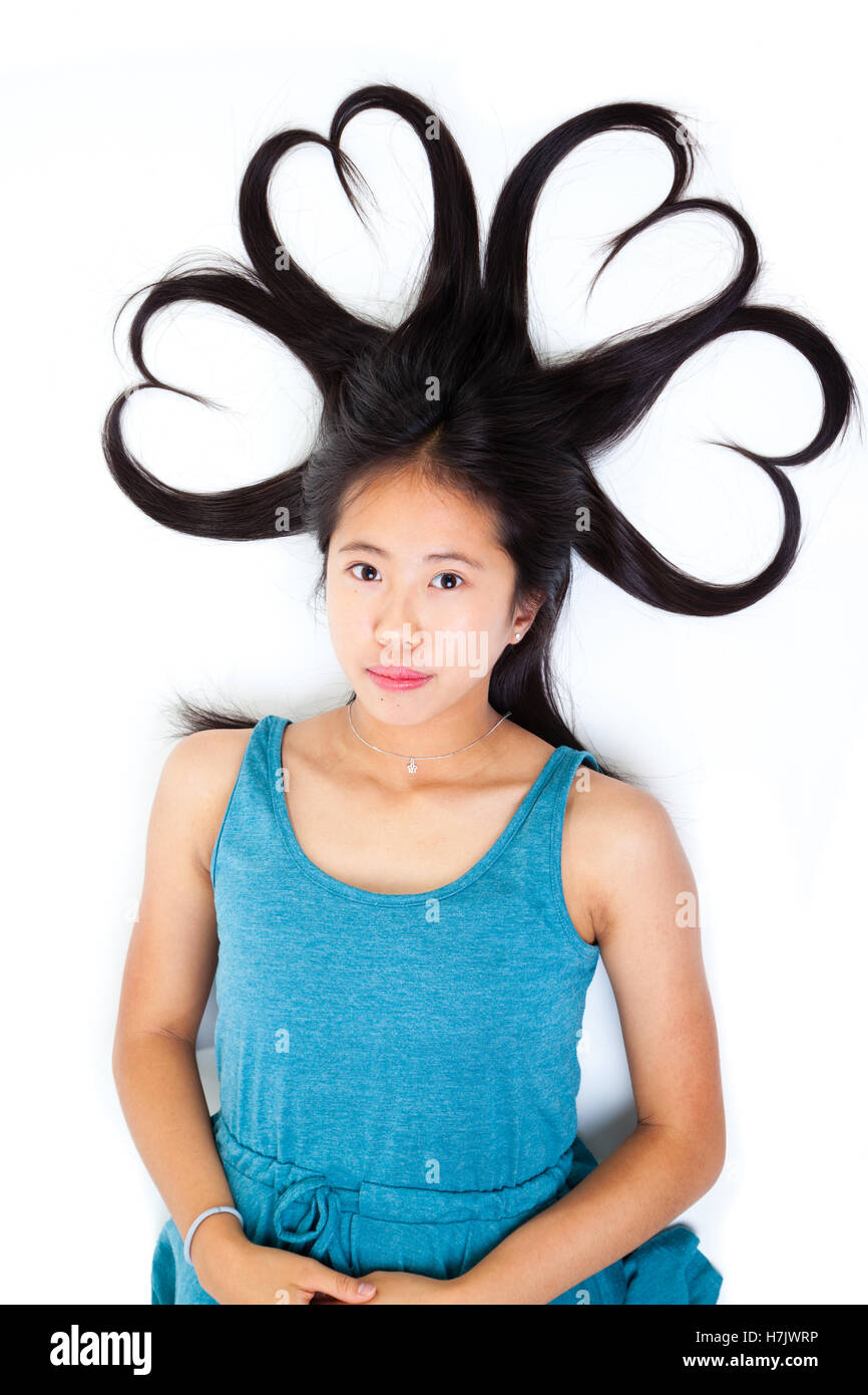Porträt eines jungen asiatischen Teen mit ihren langen Haaren zu Herzen geformt. Isoliert auf weißem Hintergrund. Stockfoto