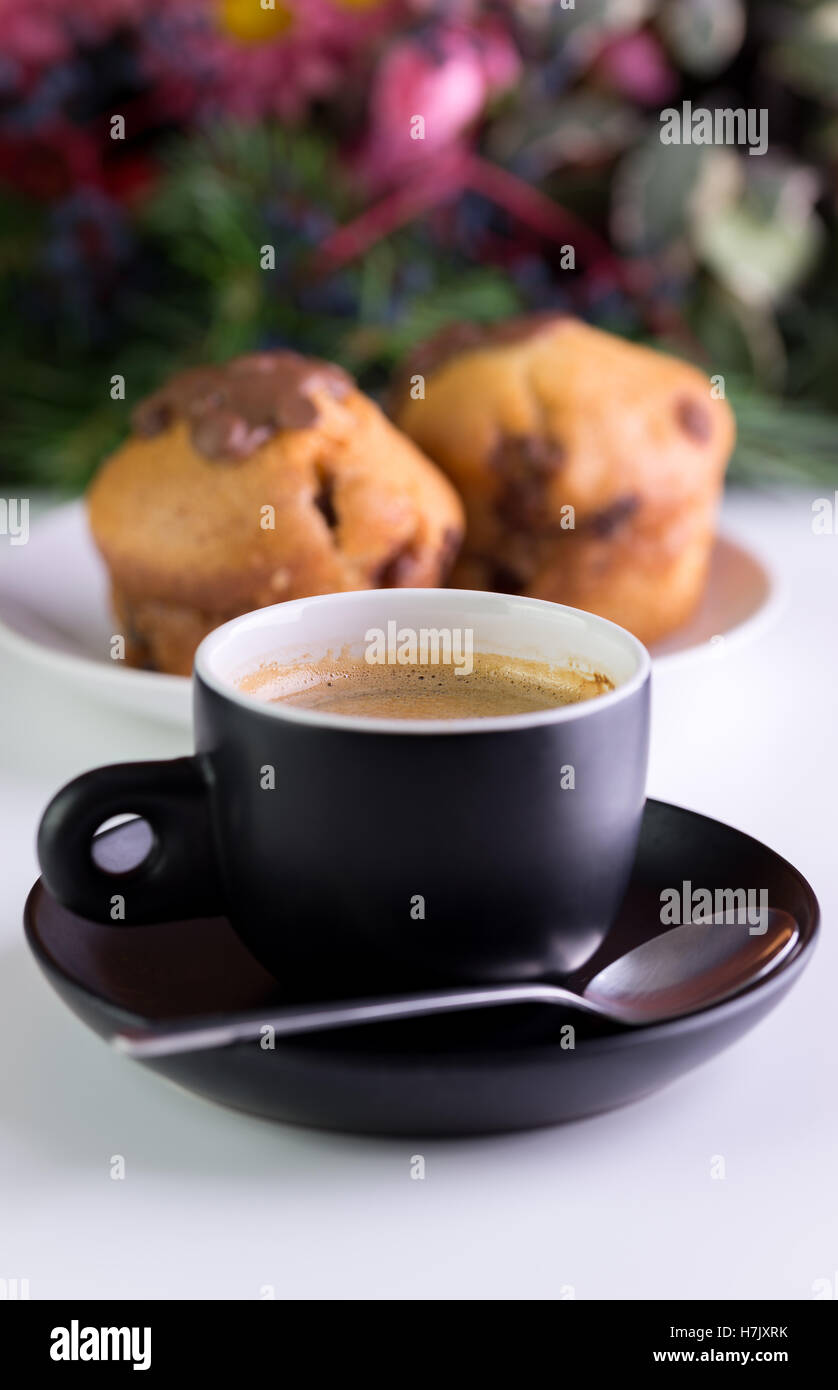 In schwarze Tasse mit Muffins hinter Kaffee am Morgen. Stockfoto