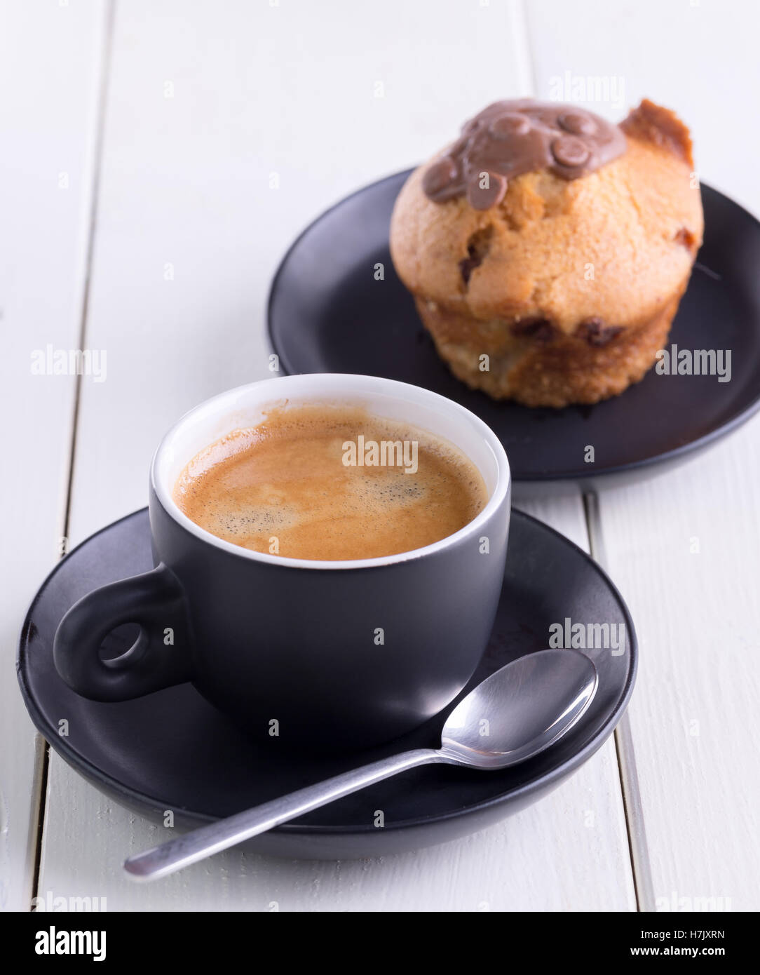 In schwarze Tasse mit Muffins hinter Kaffee am Morgen. Stockfoto