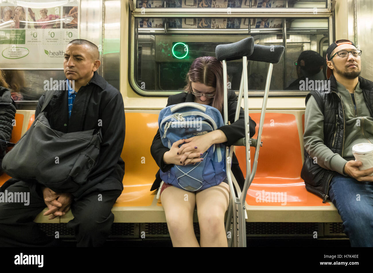Eine junge Passagierin mit Krücken auf der Fahrt durch New York U-Bahn mit zwei Fremden Stockfoto