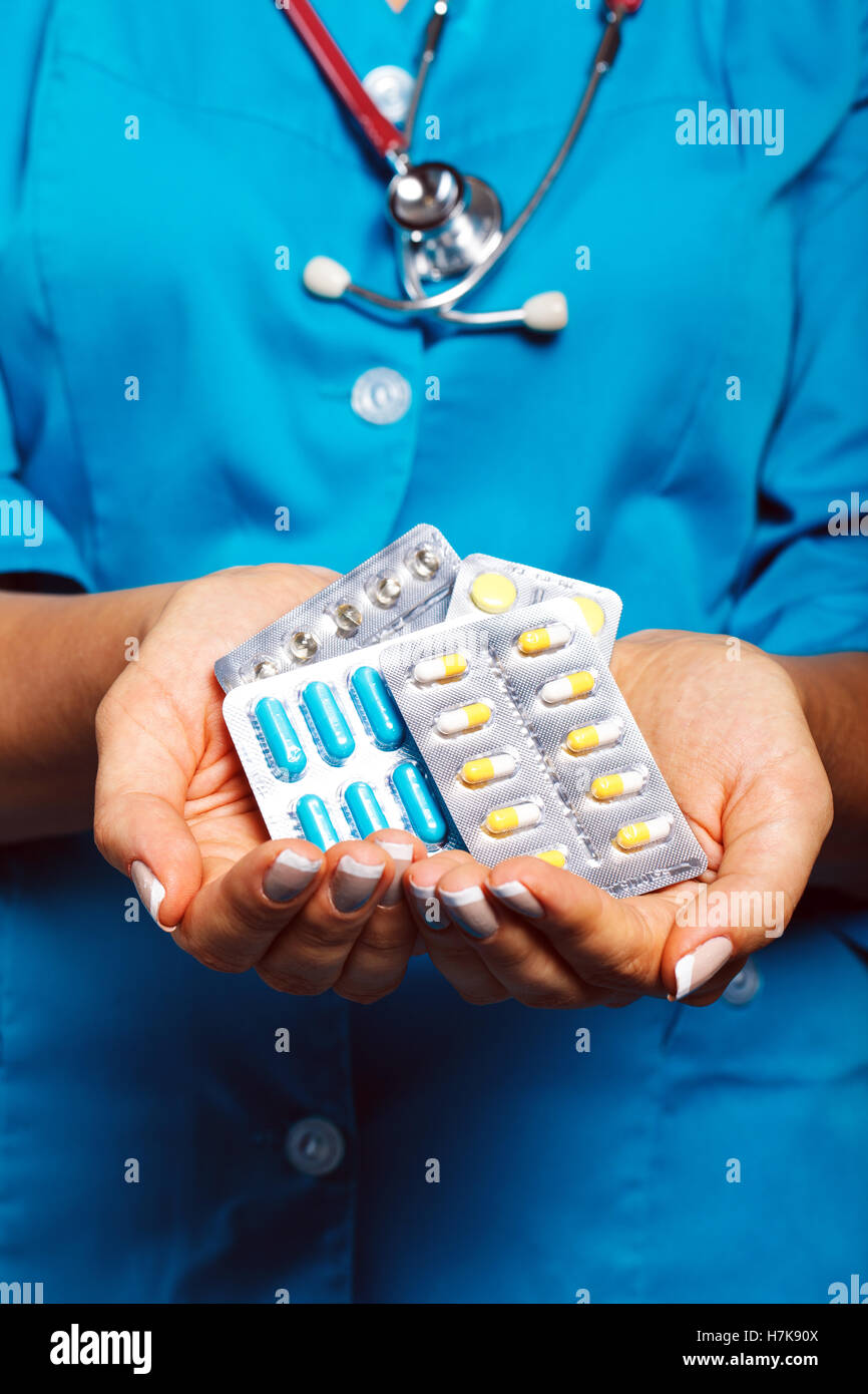 Arzt mit Pillen in der hand hautnah im Studio auf blauem Hintergrund Stockfoto
