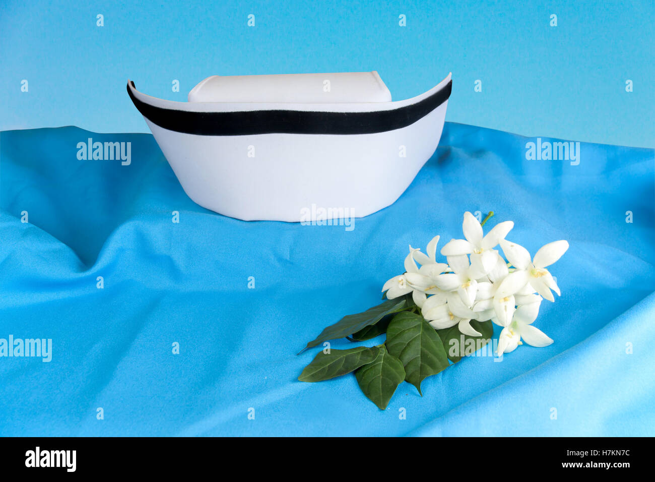 Weißer Hut Krankenschwester und Millingtonia Hortensis Blumen auf blauem Stoff. Symbol für Thailand und Thai traditionelle Medizin Pflege. Stockfoto