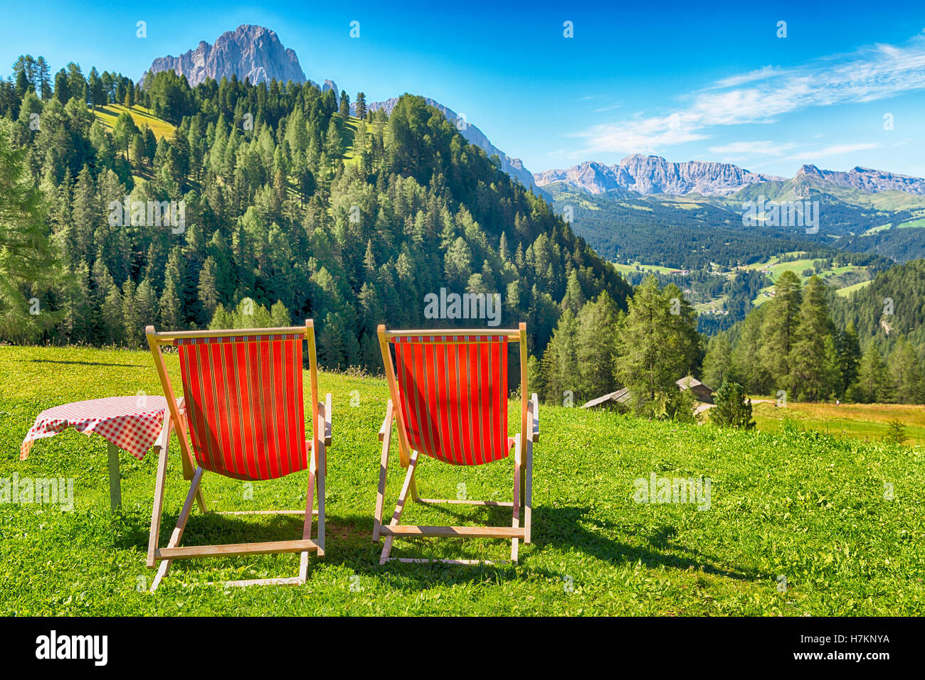 Liegestühle und Tisch auf dem Rasen mit Blick auf die Berge und das Tal im Sommer Stockfoto