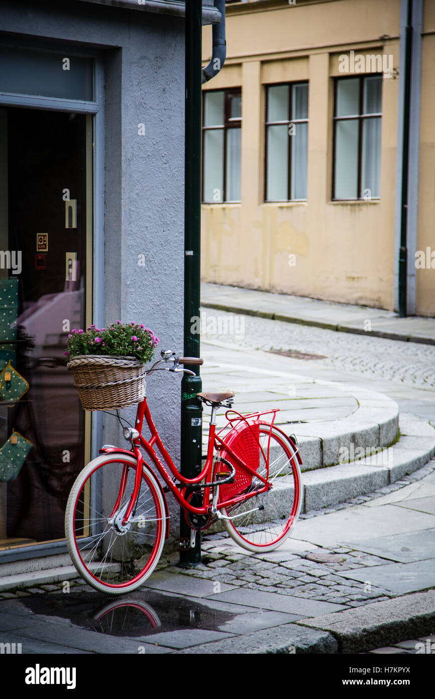 Ein rotes Fahrrad mit Blumen im Korb, abgestellt auf einer Straße in Stavanger, Norwegen. Stockfoto