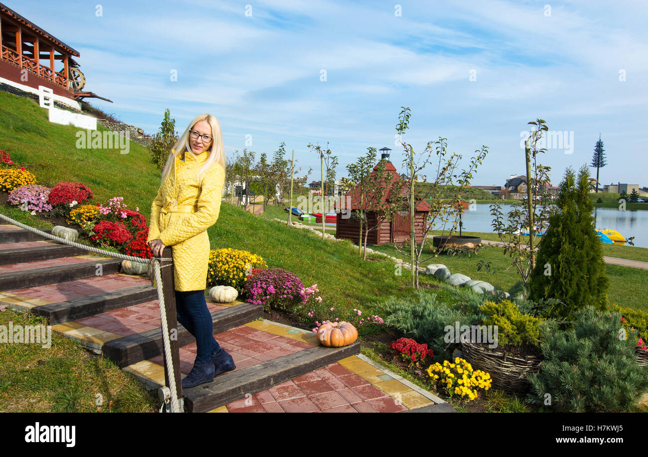 schöne Blondine mit einem gelben Mantel von hellen Farben Stockfoto